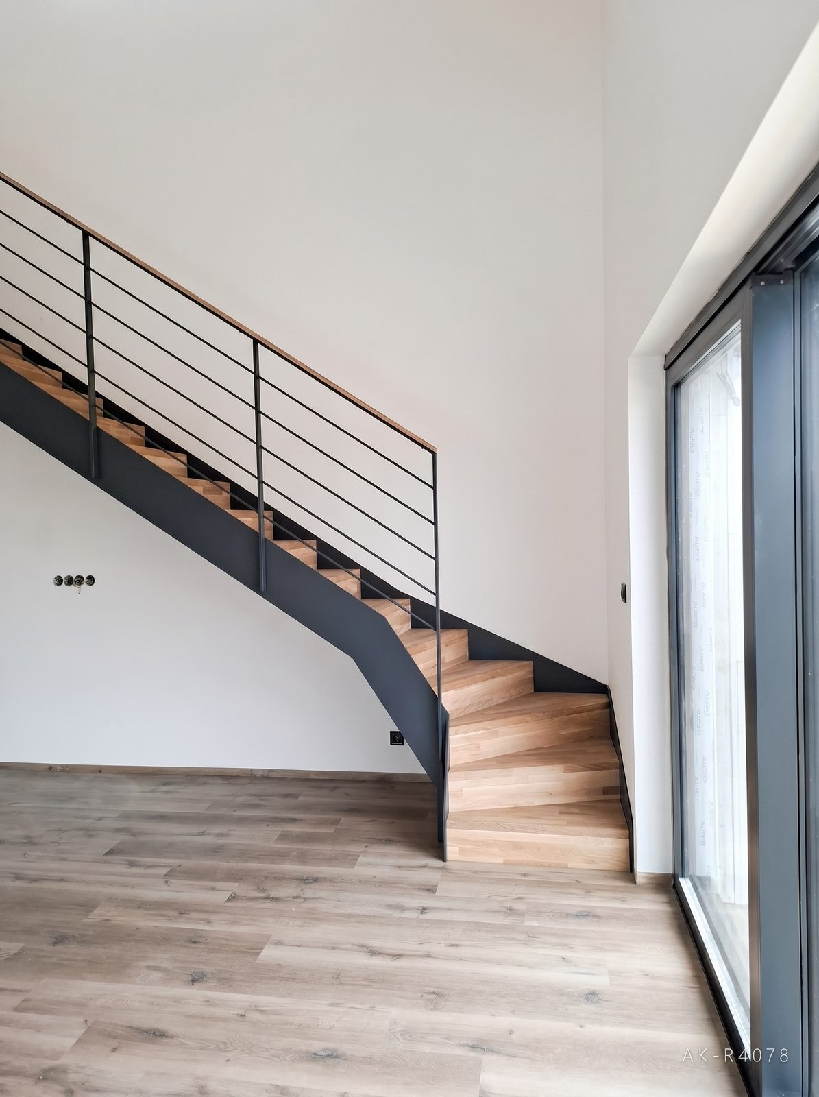 Lomené schodiště s podstupnicemi, antracitové schodnice a zábradlí. Vytváří prostor pro plánovanou kuchyňskou linku v minimalistickém rodinném domě v Ejpovicích, foto 1/5