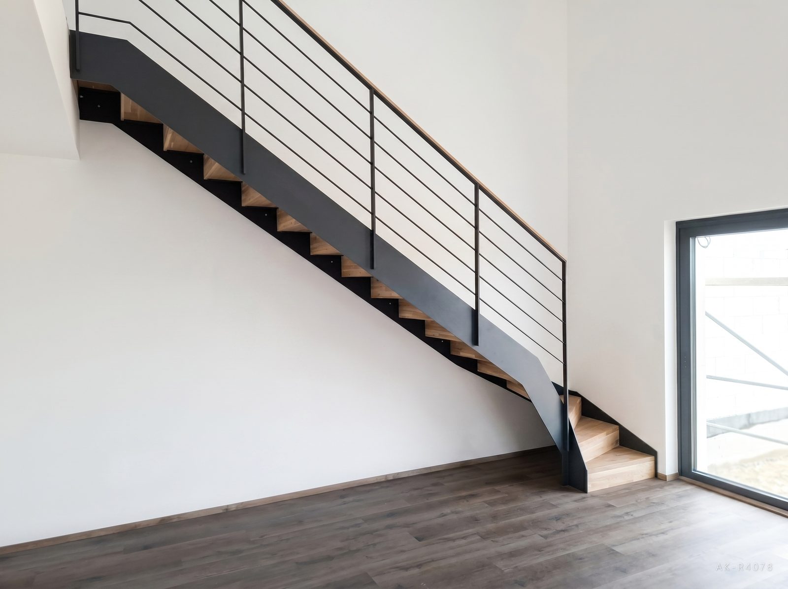 Lomené schodiště s podstupnicemi, antracitové schodnice a zábradlí. Vytváří prostor pro plánovanou kuchyňskou linku v minimalistickém rodinném domě v Ejpovicích, foto 2/5