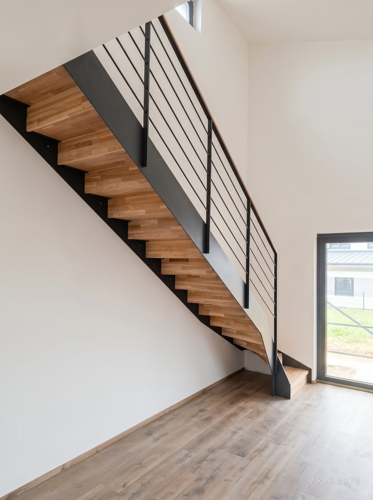 Lomené schodiště s podstupnicemi, antracitové schodnice a zábradlí. Vytváří prostor pro plánovanou kuchyňskou linku v minimalistickém rodinném domě v Ejpovicích, foto 3/5