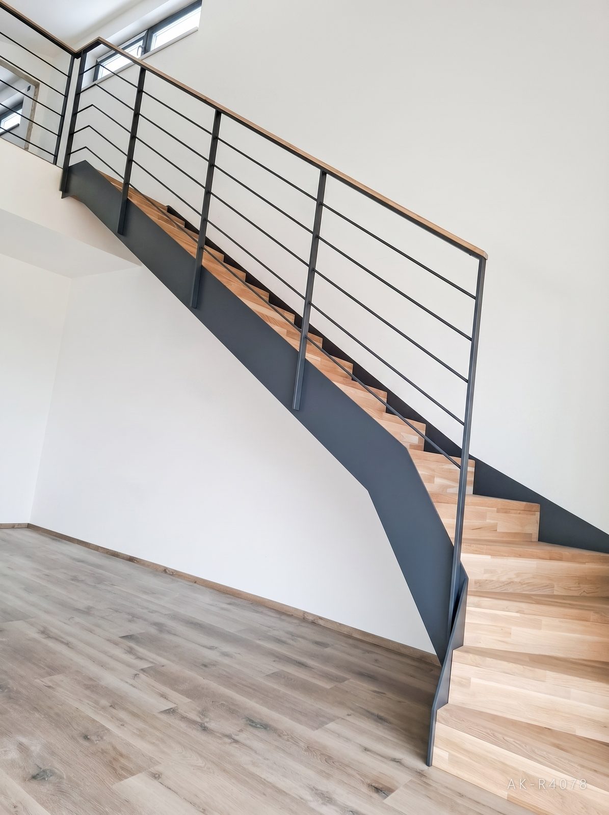 Lomené schodiště s podstupnicemi, antracitové schodnice a zábradlí. Vytváří prostor pro plánovanou kuchyňskou linku v minimalistickém rodinném domě v Ejpovicích, foto 4/5